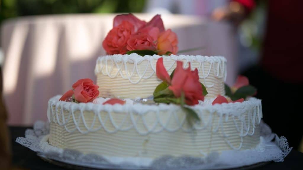 Two-tiered white cake with reddish flowers